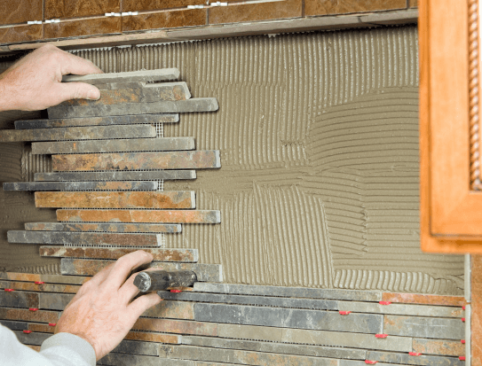 a person using a hammer to tile a wall